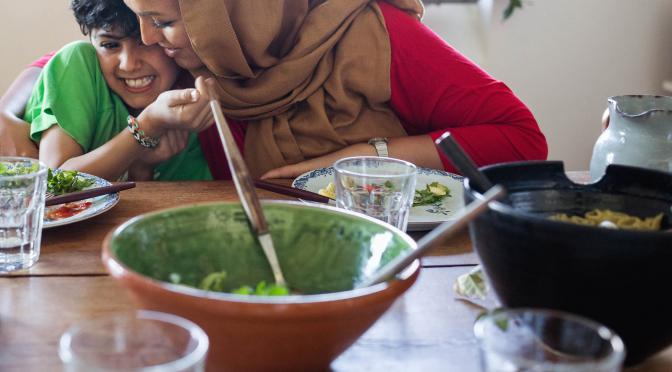 Woman hugging child at table during meal time.