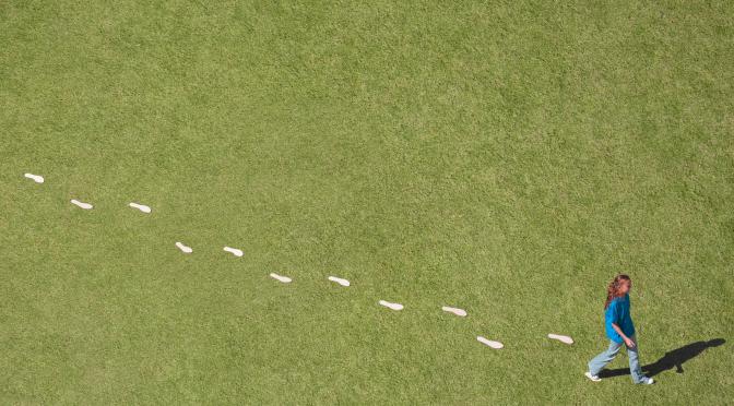 Woman walking on grass leaving footprints behind