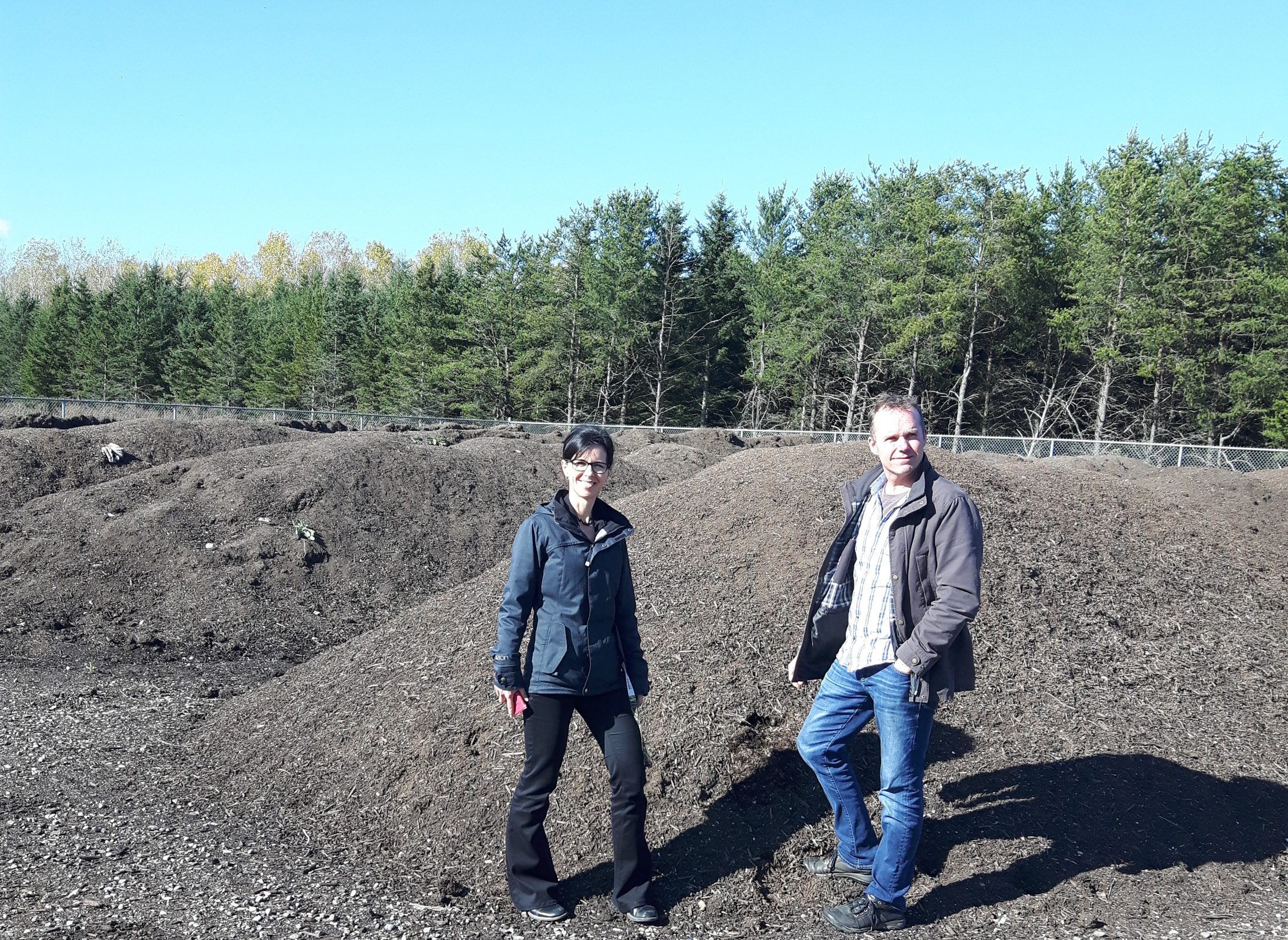 Man and woman standing in front of landfill