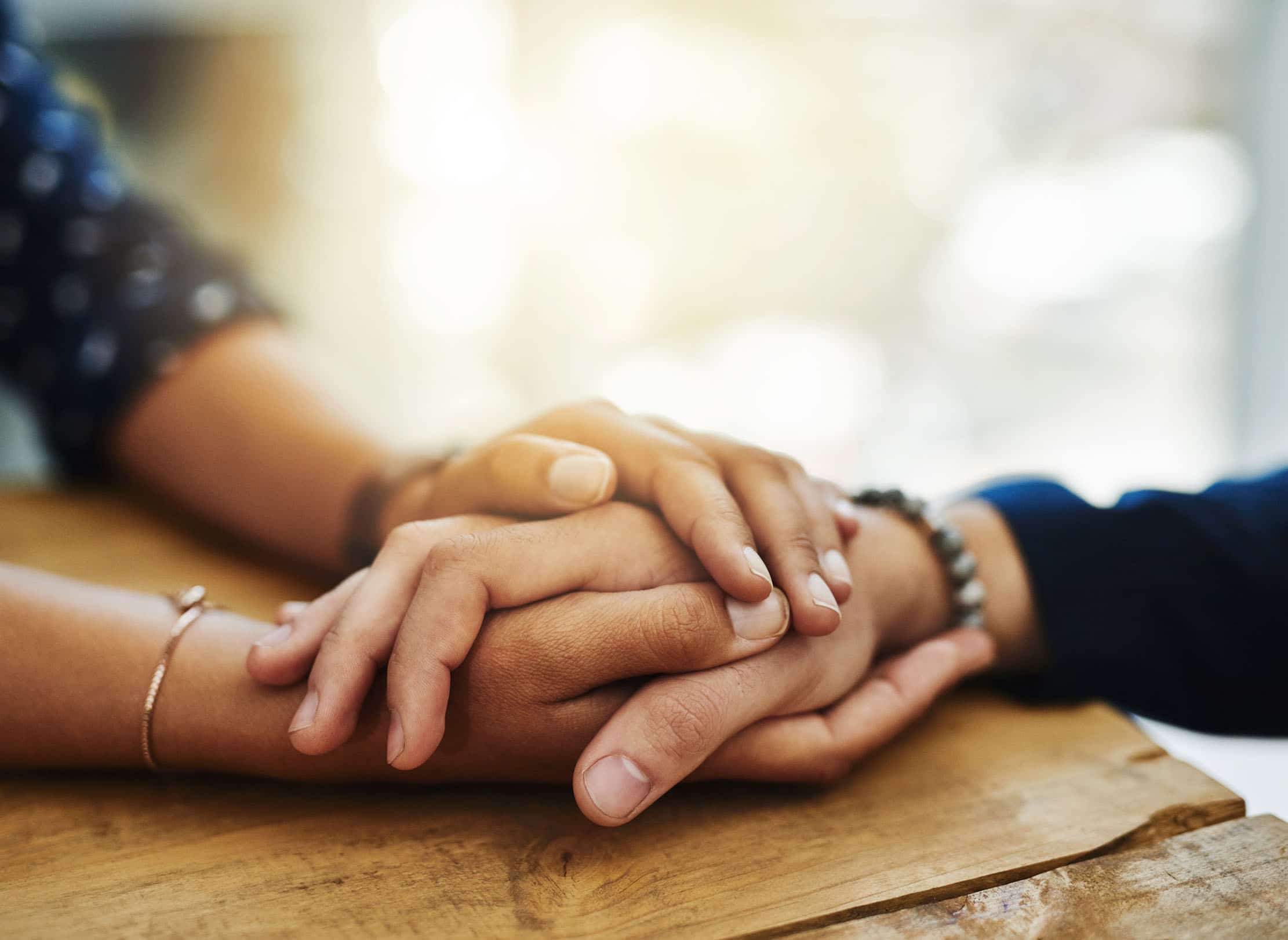 Closeup of two people holding hands in comfort.