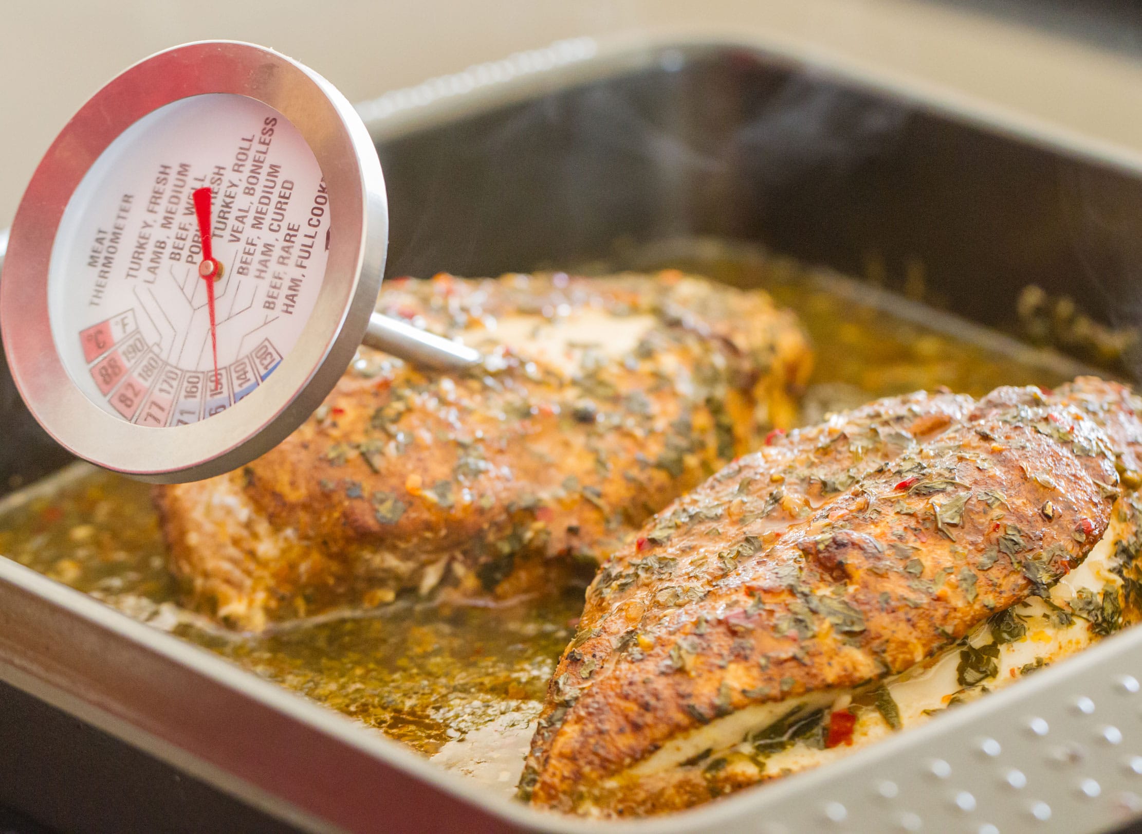 Checking internal temperature of a chicken breast with a meat thermometer.