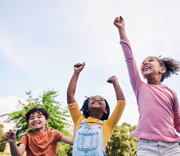 trois enfants souriant avec les bras en l'air