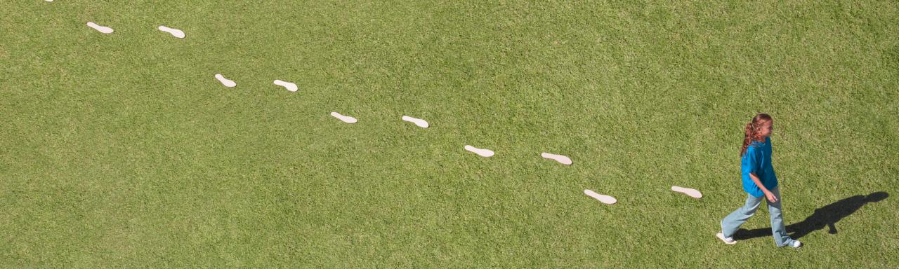 Woman walking on grass leaving footprints behind