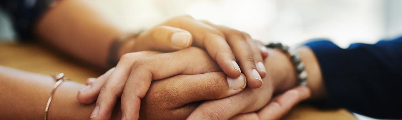 Gros plan de deux personnes se tenant les mains en signe de réconfort.
