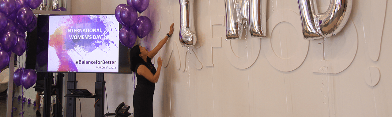 Employee putting up balloons in Maple Leaf office lobby.