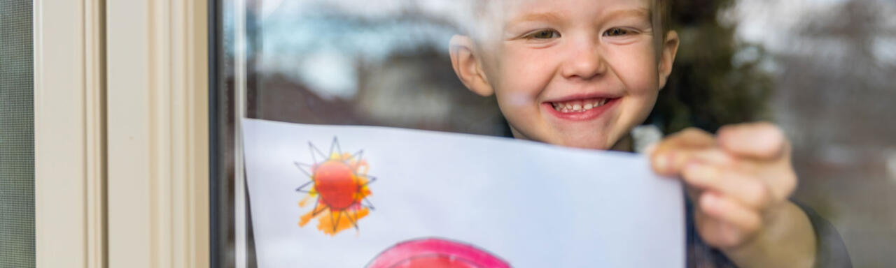 A young boy holding up his picture