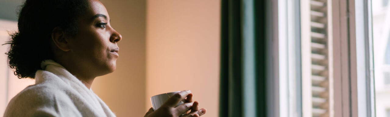 Woman holding a cup and looking out a window