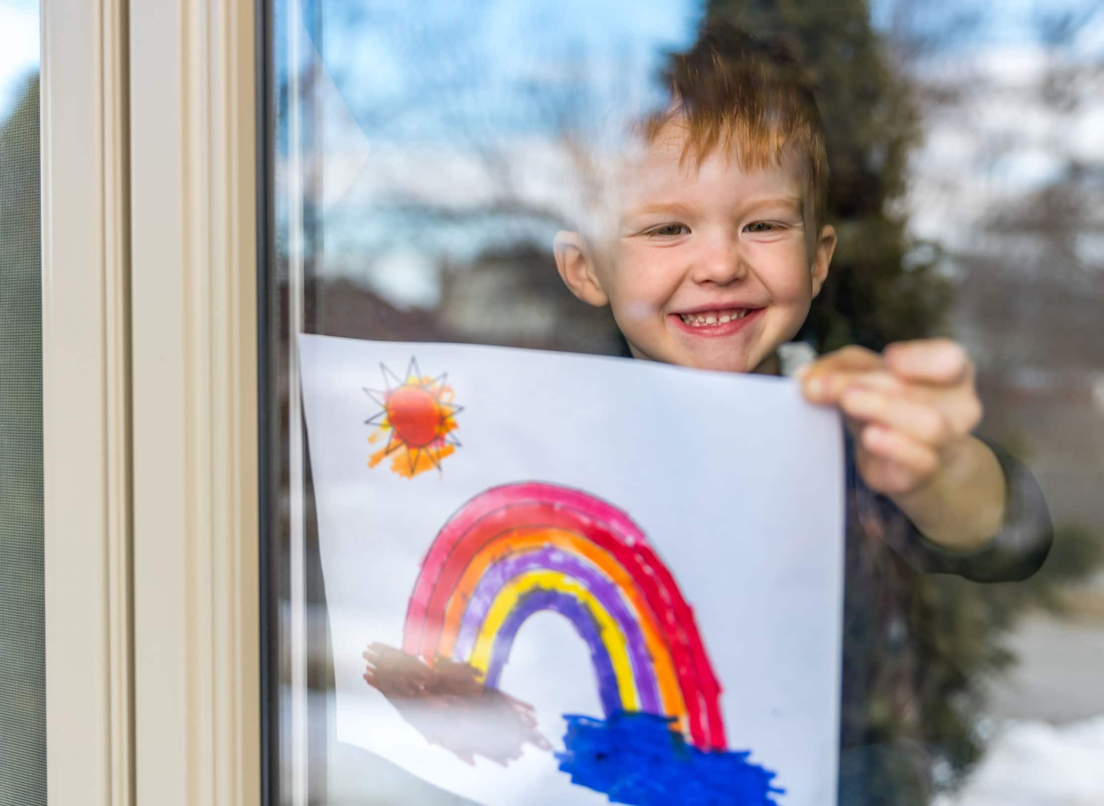 A child taping a picture to a window