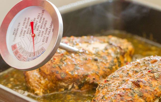 Checking temperature of chicken with a meat thermometer