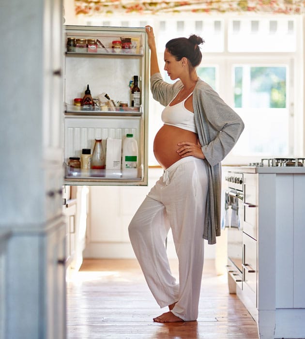 Pregnant woman looking into fridge