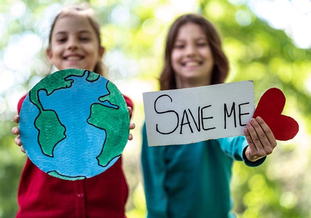 Two girls holding up save the earth signs