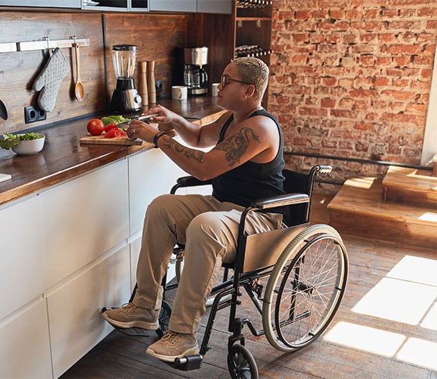 person in a wheelchair cooking in a kitchen