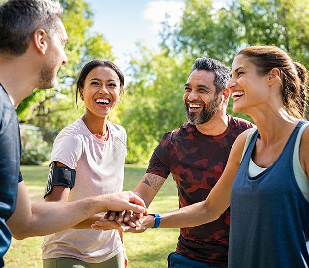 group of four adults, two women and two men, huddled in a circle, smiling and talking